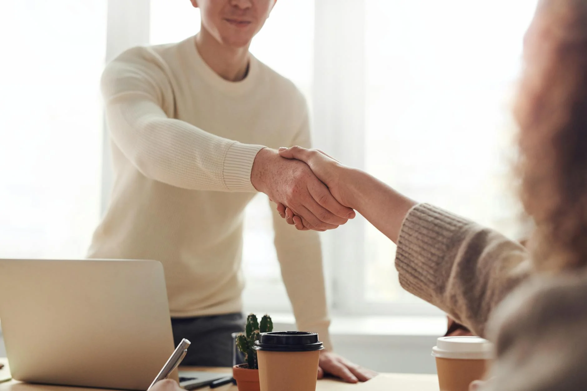 Person schüttelt einer Bewerberin oder einem Bewerber die Hand.