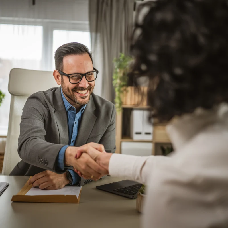 Recruteur et candidat se serrant la main lors d'un entretien d'embauche.