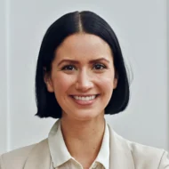 Portrait d'une femme souriante portant une veste claire.