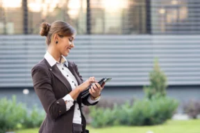 Personne en tenue professionnelle utilisant une tablette en extérieur.